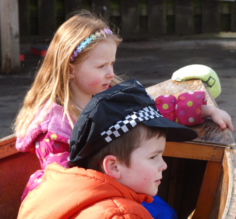 Photo of two children playing outdoors in a wooden boat at Longscroft